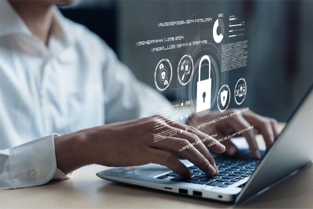 Person typing on a laptop with digital cybersecurity lock and analytics interface overlay.